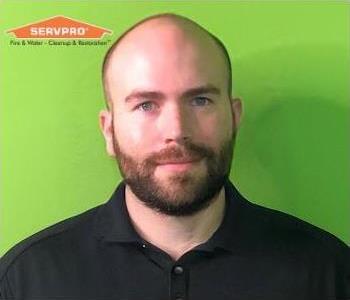 Male manager in front of green background with orange SERVPRO logo