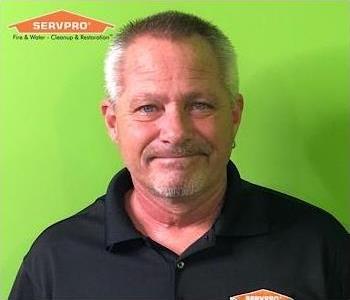 Male manager in front of green truck with orange SERVPRO logo