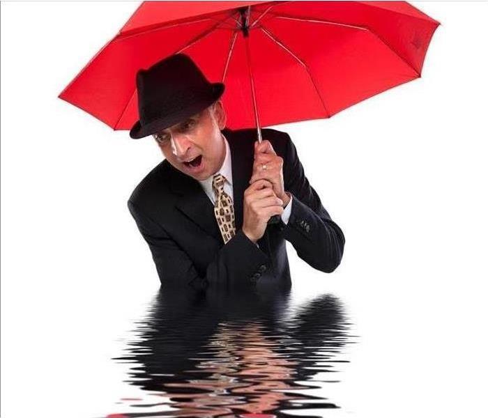 Man waste deep in water with red umbrella
